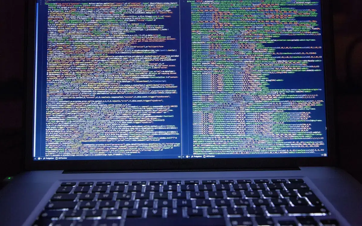 Lines of source code on a laptop screen in a dark room